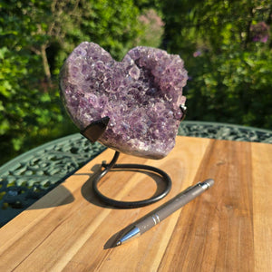 Amethyst Druse Amethyst Geode in Herzform mit Metallsockel 16x12x13cm - NR-38 auf einem Tisch im Freien