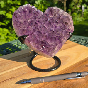 Amethyst Druse Amethyst Geode in Herzform mit Metallsockel 15x15x12cm - NR-41 auf Holzständer im Freien.