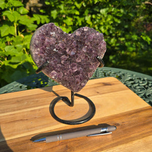 Amethyst Druse Amethyst Geode in Herzform mit Metallsockel 18x15x10cm - NR-44 auf Holzunterlage mit Kugelschreiber.