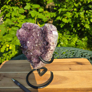Amethyst Druse Amethyst Geode in Herzform mit Metallsockel 18x16x10cm - NR-45 auf einem Tisch im Freien.
