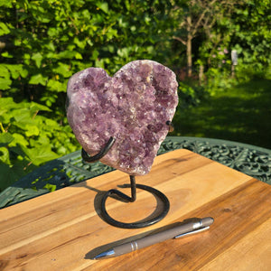 Amethyst Druse Amethyst Geode in Herzform mit Metallsockel 18x16x10cm - NR-45 auf einem Tisch im Freien.