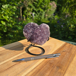 Amethyst Druse Amethyst Geode in Herzform mit Metallsockel 11x10x9cm - NR-48 auf Holzunterlage in natürlicher Umgebung.
