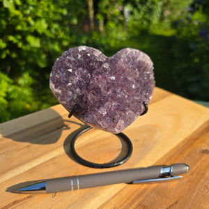 Amethyst Druse Amethyst Geode in Herzform mit Metallsockel 11x10x9cm - NR-48 auf einem Holztisch mit Stift