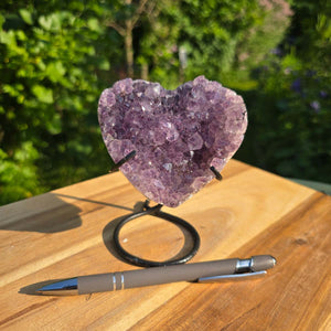 Amethyst Druse Amethyst Geode in Herzform mit Metallsockel 12x9x8cm - NR-49 auf Holzuntergrund mit Stift.