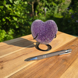 Amethyst Druse Amethyst Geode in Herzform mit Metallsockel 10x9x7cm - NR-55, präsentiert auf einem Holztisch.