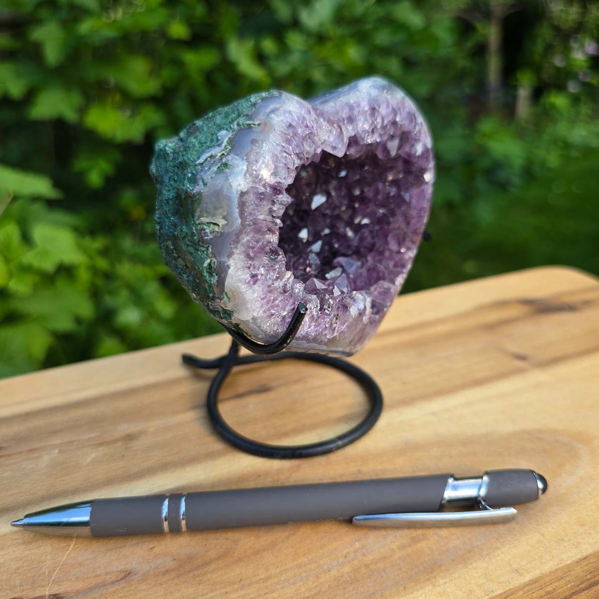 Amethyst Druse Amethyst Geode in Herzform mit Metallsockel 11x10x9cm - NR-60 auf Holzstand, Blick auf Kristallstruktur.