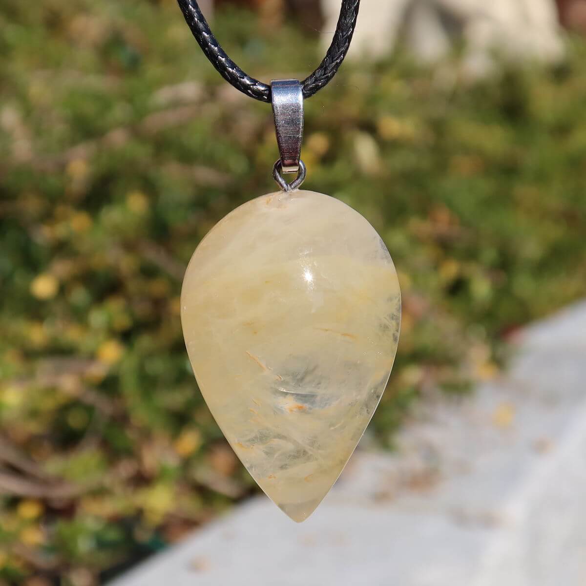 Limonit Quarz Golden Healer Anhänger - Lebensfreude - Nr. 5, funkelnder Quarz mit goldbraunen Einschlüssen vor grünem Hintergrund