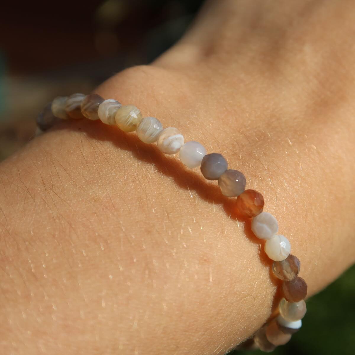 Faceted agate gemstone bracelet in various colors on wrist, showcasing unique patterns and vibrant shades, 4-6-8mm beads.