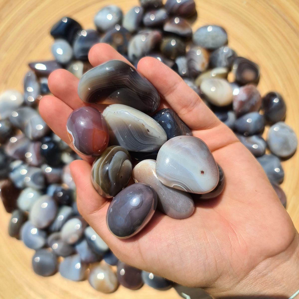 Hand holding Achat Botswana - Handschmeichler stones in various natural colors