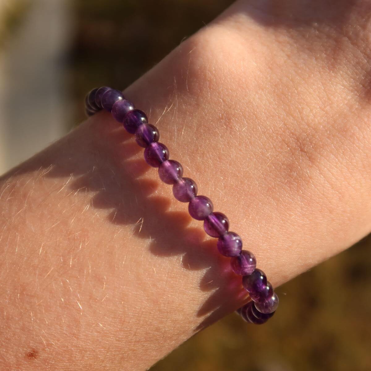 Hand holding amethyst bracelet in vibrant violet, available at Online Shop Steinwelten Graz and Wiener Neustadt, sizes 4-6-8mm.