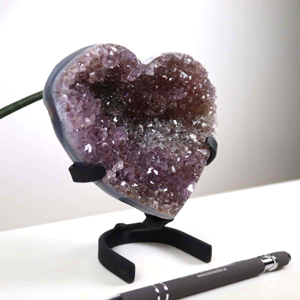 Amethyst Druse Amethyst Geode in Herzform mit Metallsockel 10x12cm - NR-7, präsentiert auf einem Schreibtisch, neben einem Stift.