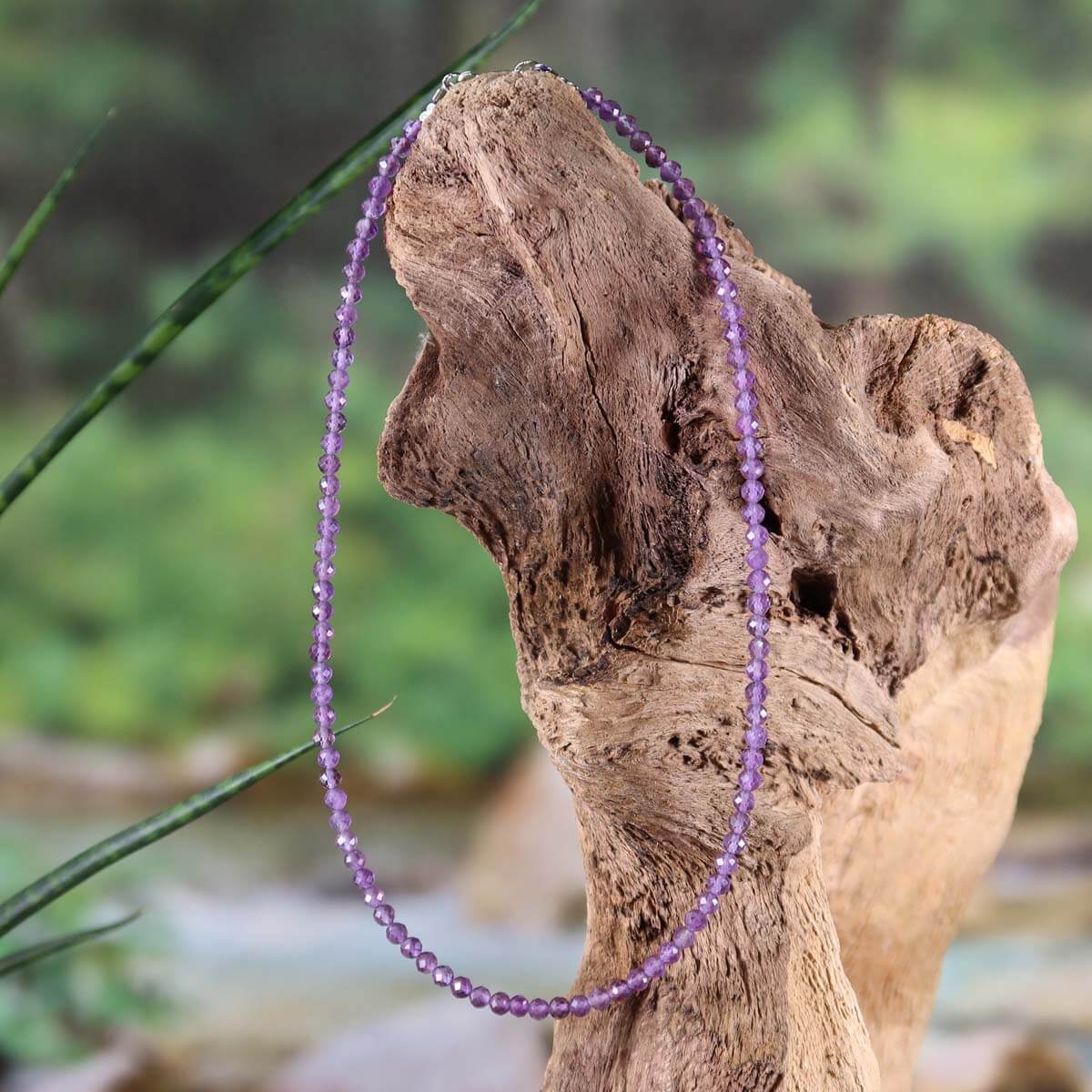 Faceted amethyst gemstone necklace 42cm on wood background, elegant handmade jewelry for harmony and spirituality. Steinwelten.