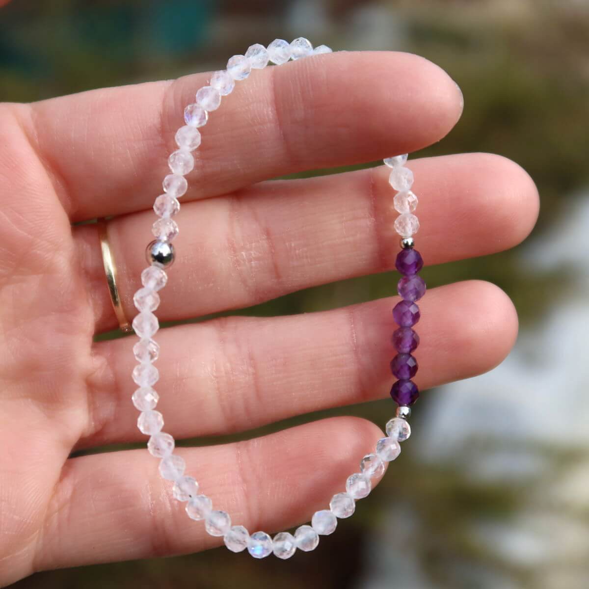 Hand wearing a handmade amethyst and white labradorite bracelet with faceted gemstone beads, 17cm in length.