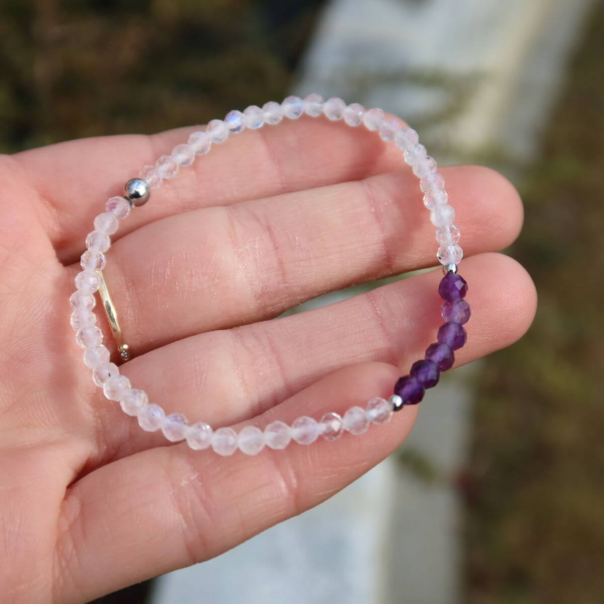 Hand holding amethyst and white labradorite gemstone bracelet, showcasing purple and light blue beaded design, 17cm long.