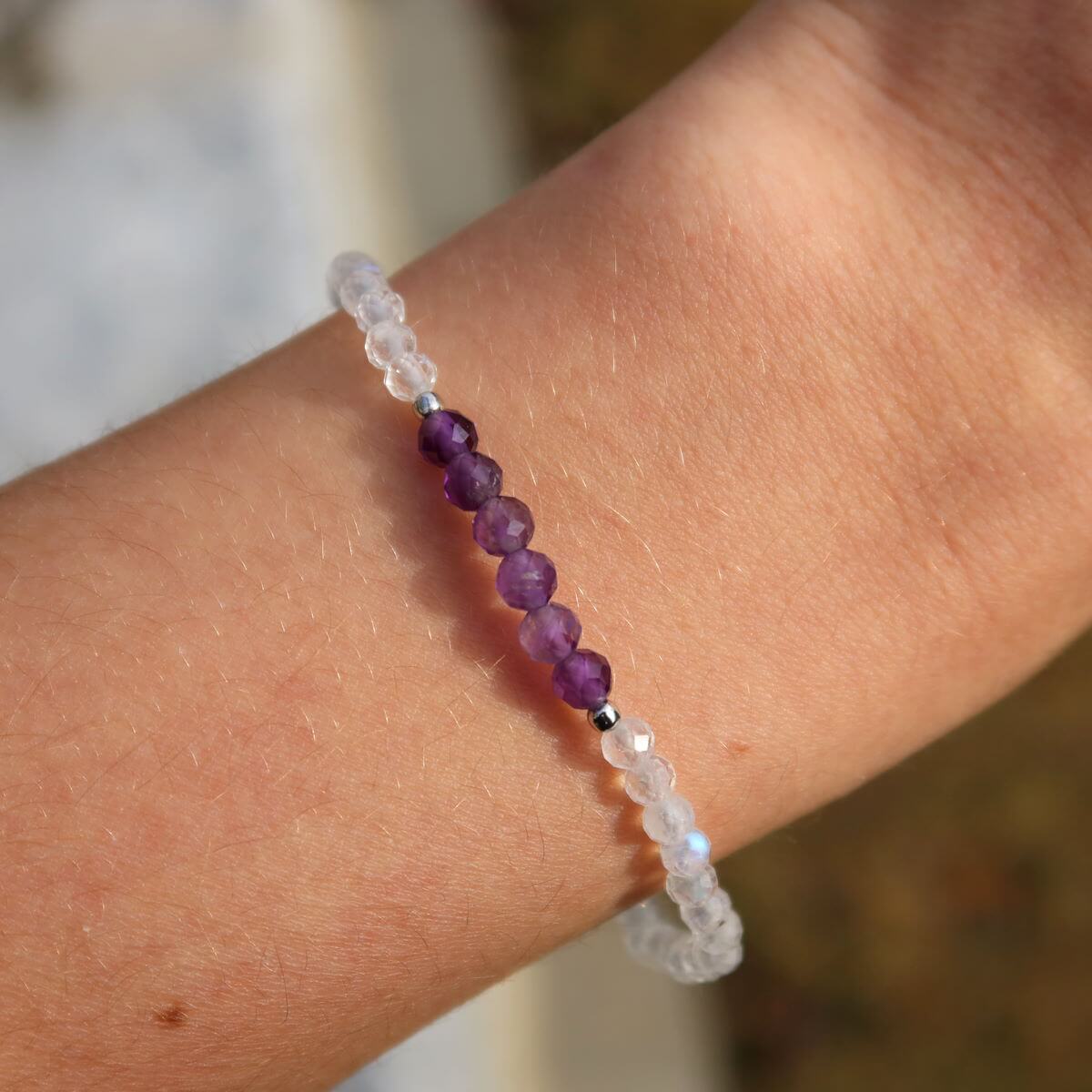 Hand wearing a handmade amethyst and white labradorite bracelet with faceted gemstone beads, 17cm in length.