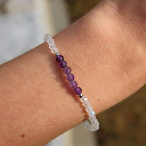 Hand wearing a handmade amethyst and white labradorite bracelet with faceted gemstone beads, 17cm in length.
