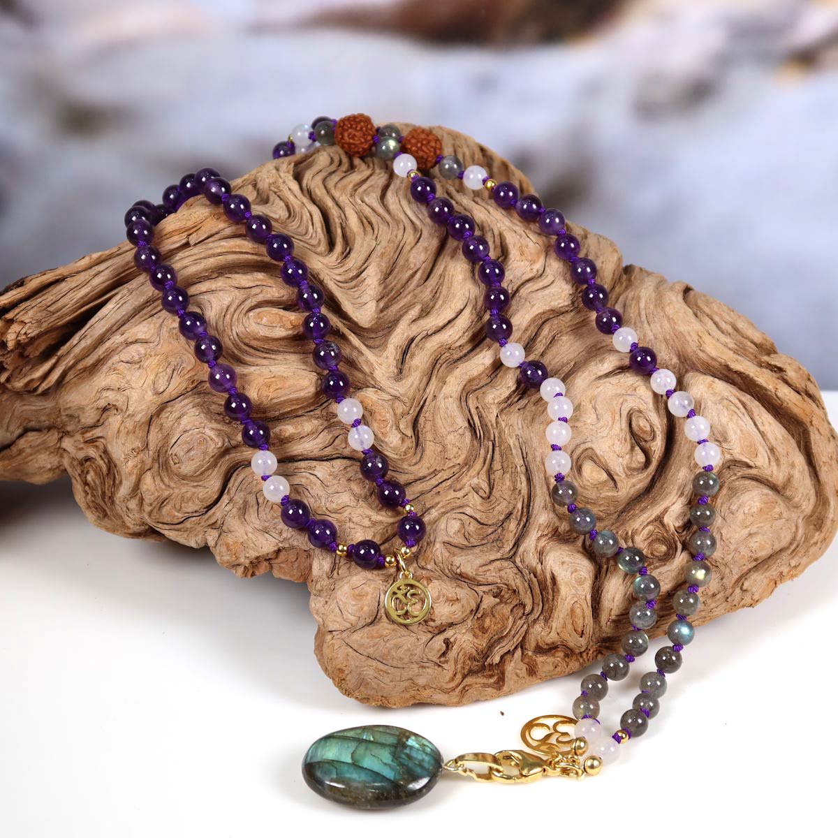 Mala Kette mit Amethyst, Labradorit und Rudraksha-Perlen auf Holz, Labradorit Anhänger im Fokus, spirituell, Unikat Nr. 20