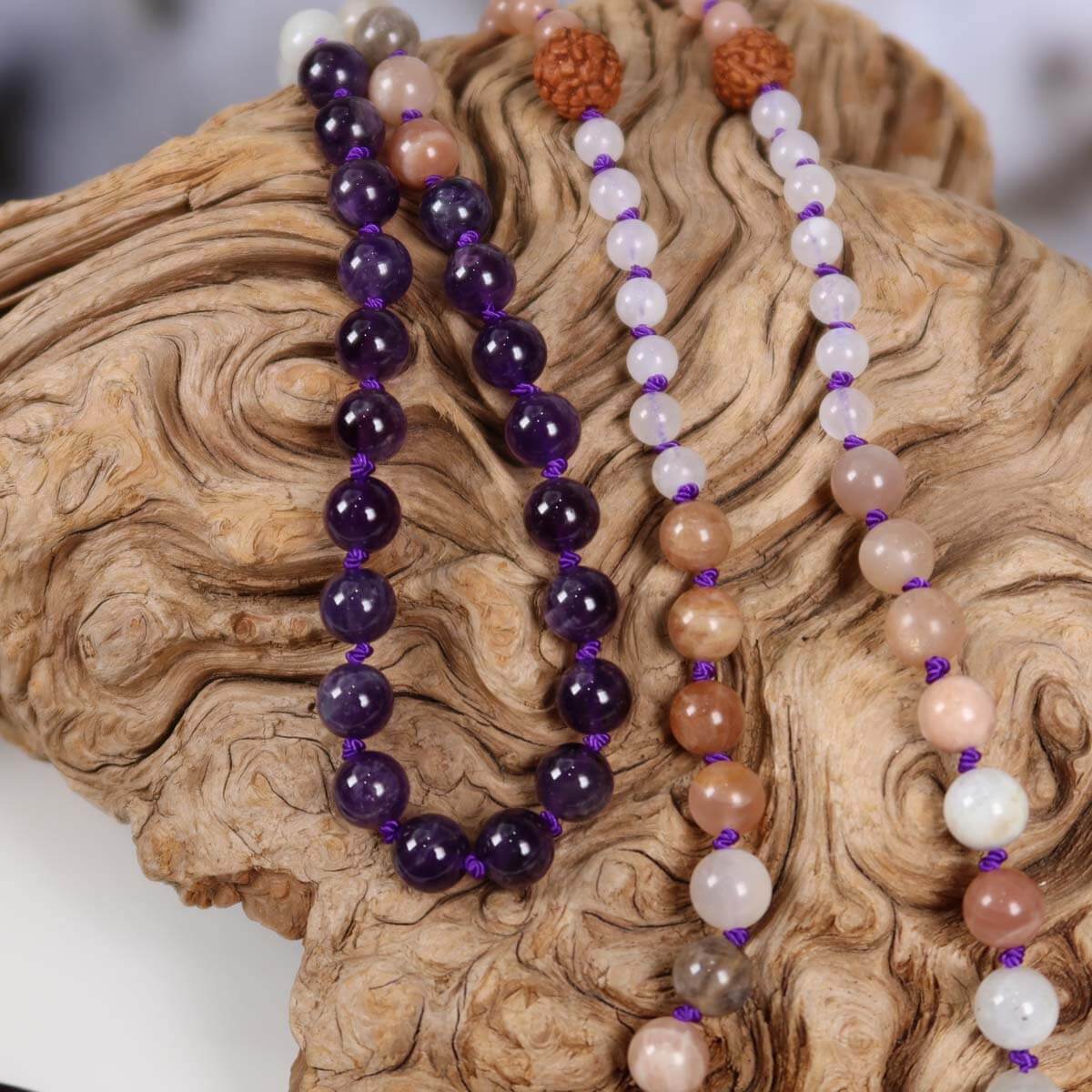 Handcrafted mala necklace with amethyst, moonstone, labradorite, rudraksha beads and amethyst pendant on driftwood display.