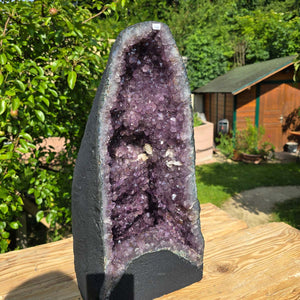 Amethyst Druse – Geode - 48x24x23cm und 23,6kg – Steinwelten OG - Nr. 146 auf Holzoberfläche vor grünem Hintergrund