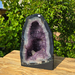 Amethyst Druse – Geode - 35x23x19cm und 17,8kg – Steinwelten OG - Nr. 198, displayed on a wooden surface outdoors.