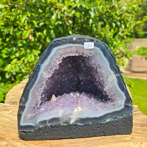 Amethyst Druse – Geode - 16x18x13cm und 4,2kg – Steinwelten OG - Nr. 251 showcasing unique crystal structure in a garden.