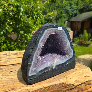 Amethyst Druse – Geode - 16x18x13cm und 4,2kg – Steinwelten OG - Nr. 251 on display outdoors, showcasing its unique crystal structure.