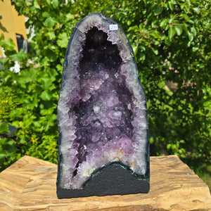 Amethyst Druse – Geode - 33x18x15cm und 9,4kg – Steinwelten OG - Nr. 275 displayed on a wooden stand outdoors.