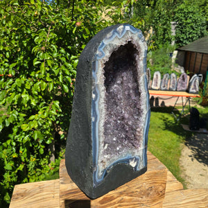 Amethyst Druse – Geode - 47x24cm und 32,9kg – Steinwelten OG - Nr. 327, Brazilian amethyst with light violet crystals in a garden setting.