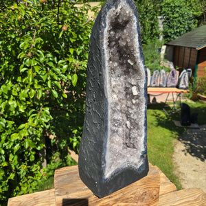 Amethyst Druse – Geode - 57x22cm und 23,1kg – Steinwelten OG - Nr. 346 in einem Garten, brasilianische Kristalle leuchten hell.