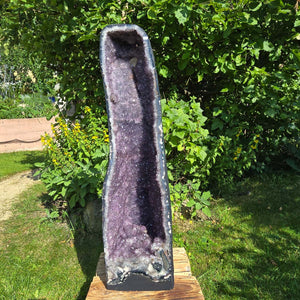 Amethyst Druse – Geode - 84x23x26cm und 45,4kg – Steinwelten OG - Nr. 361 in a garden setting.