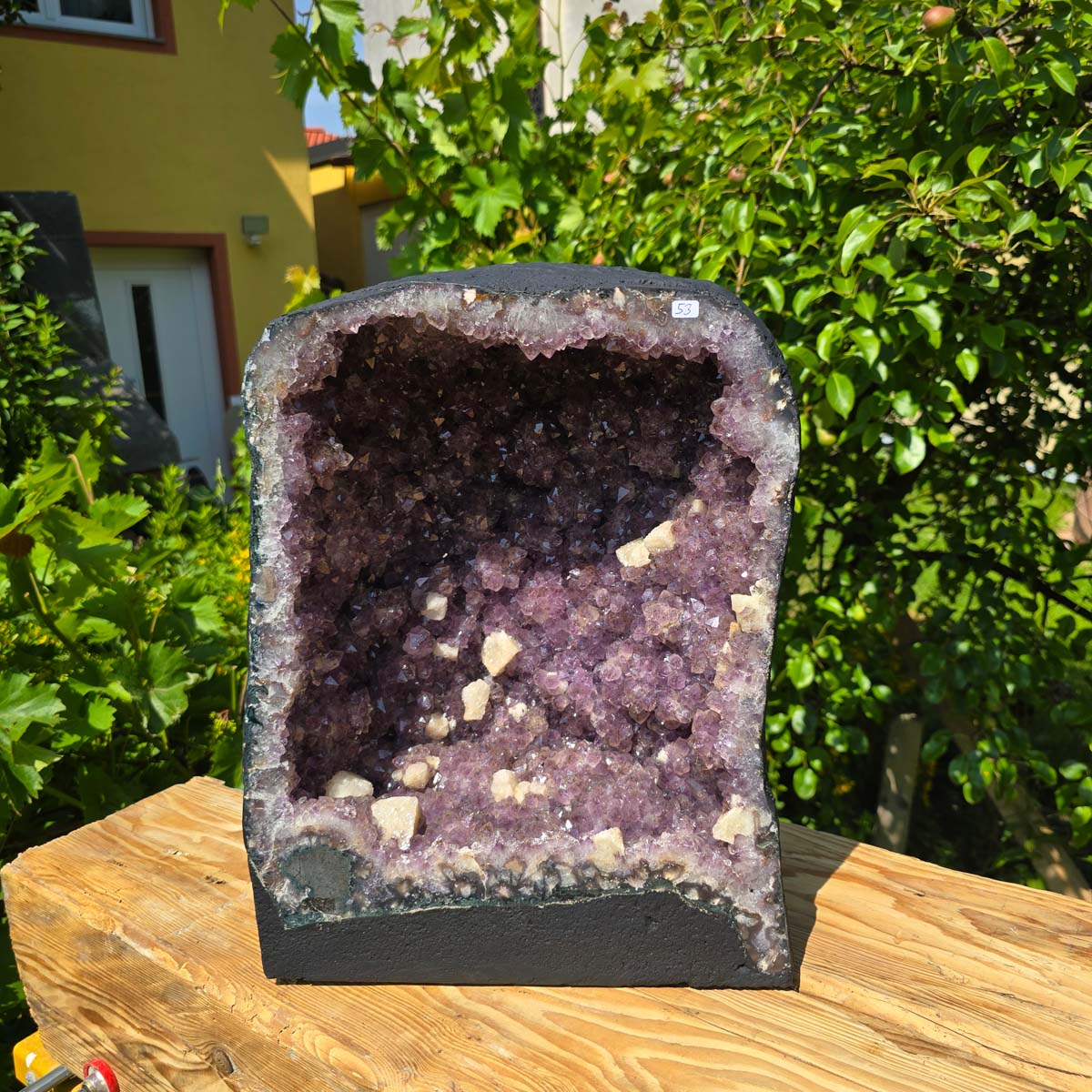 Amethyst Druse – Geode - 43x32x22cm und 31,2kg – Steinwelten OG - Nr. 53 displayed outdoors on a wooden table.