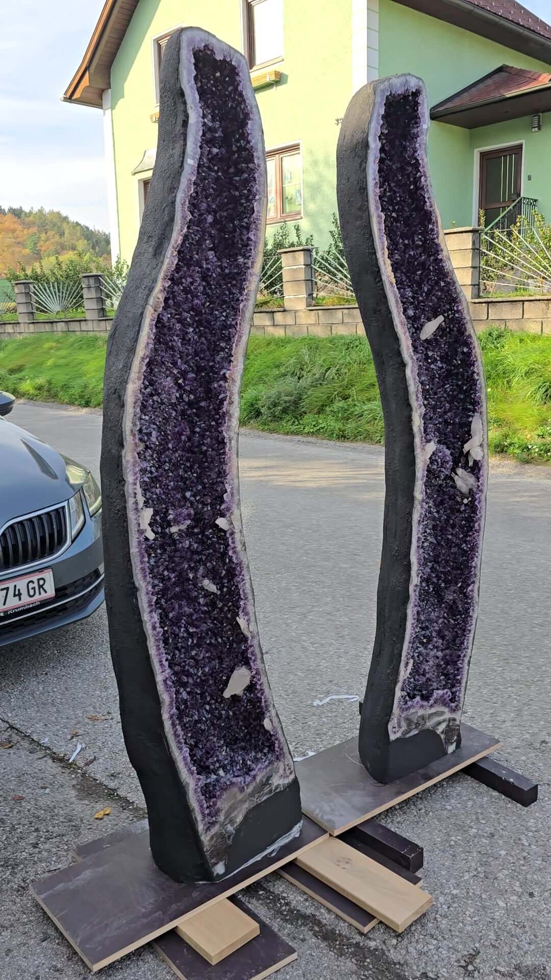 AA-quality large amethyst geode pair with deep violet crystals displayed in a garage setting