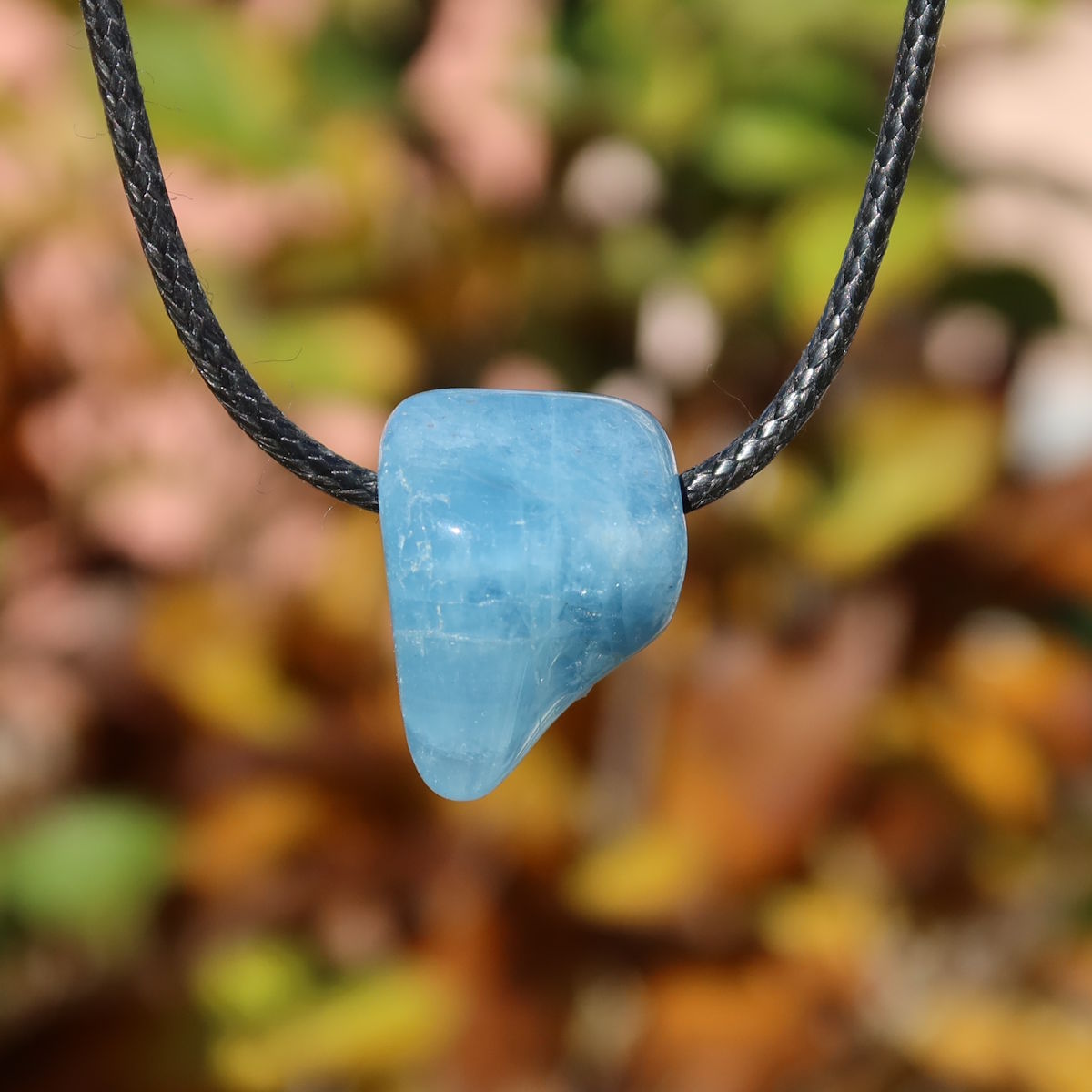 1A Qualität Aquamarin gebohrt 24mm - Ausgeglichenheit und frische Energie - UNIKAT Nr. 13, hellblauer Anhänger vor unscharfem Hintergrund