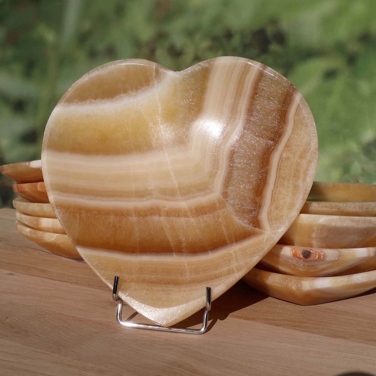 Herzförmige Aragonit-Onyx Schale, 16 cm groß, dekorativer Edelstein aus Marokko auf Holzdisplay. Produkt von Steinwelten Graz.