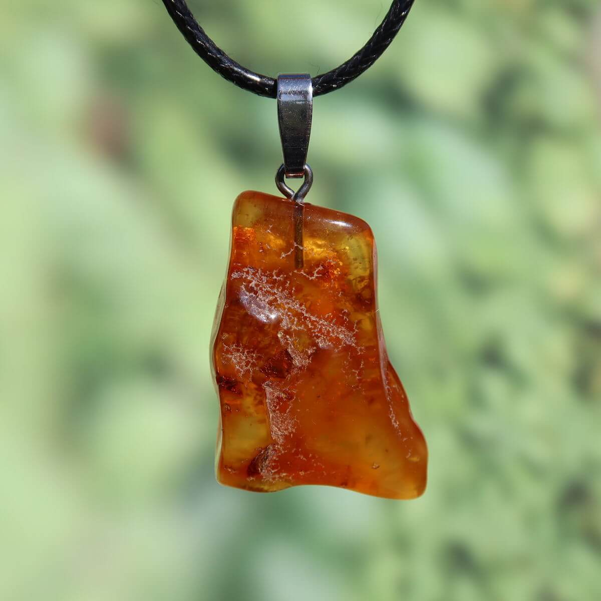 Natürlicher Bernstein Anhänger 31mm auf schwarzem Band, einzigartiges Unikat Nr. 22, sanft transparent und schimmernd im Licht.