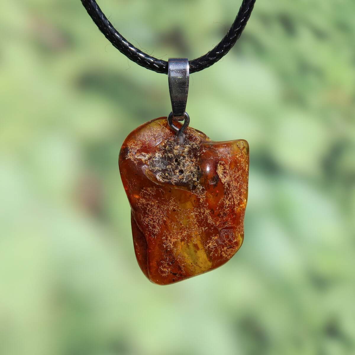 Natürlicher Bernstein Anhänger 30mm mit einzigartiger Transparenz, eingefangen auf einem grünen Hintergrund.