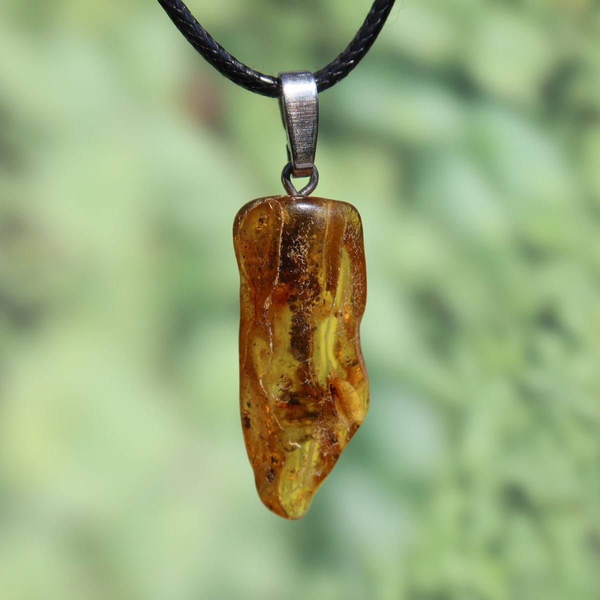 Natürlicher Bernstein Anhänger 35mm mit einzigartiger Transparenz vor grünem Hintergrund, UNIKAT Nr. 5