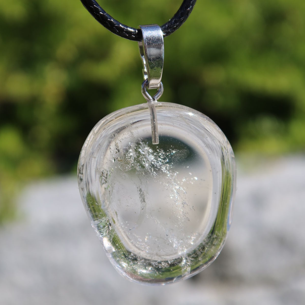 Bergkristall Anhänger 31mm mit Silberöse, klarer Stein für Gedankenfreiheit und Fokus, handgefertigtes Unikat Nr. 8 vor grünem Hintergrund