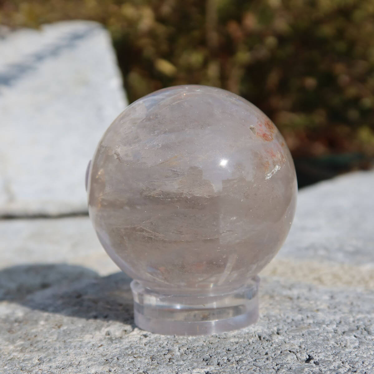 Bergkristall Kugel geschliffen UNIKAT Nr. 1, erhältlich im Online Shop Steinwelten Graz und Wiener Neustadt, handgehalten vor grünem Hintergrund.