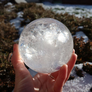 Bergkristall Kugel – Natürliche Kristallkugel 90mm Durchmesser Nr. 27, gehalten in der Hand in natürlichem Licht.