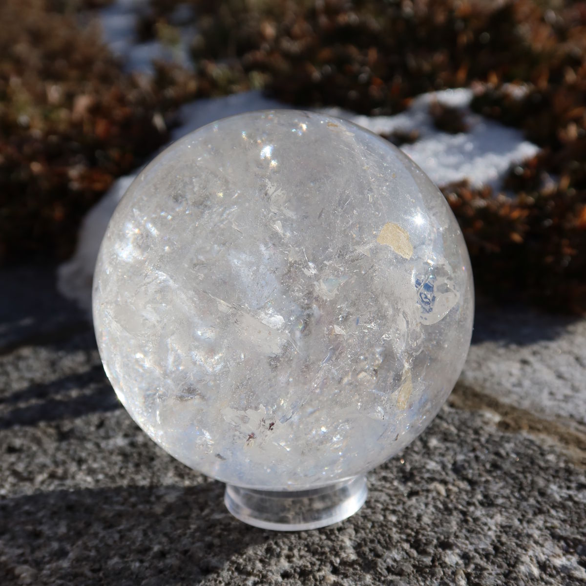 Bergkristall Kugel – Natürliche Kristallkugel 90mm Durchmesser Nr. 28 auf einem Stein im Freien, zeigt natürliche Klarheit und Schönheit.