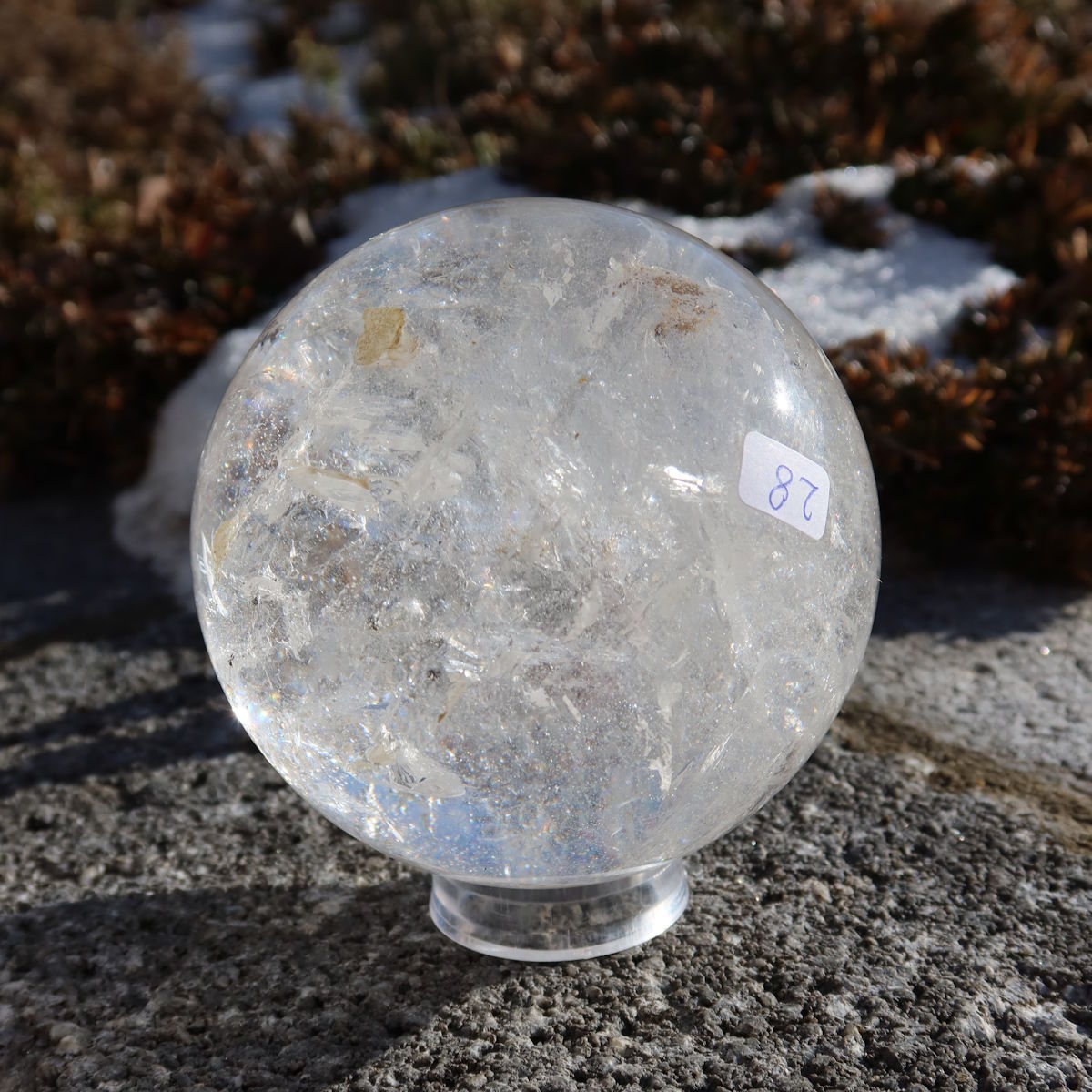 Bergkristall Kugel – Natürliche Kristallkugel 90mm Durchmesser Nr. 28 auf einem Stein im Freien, zeigt natürliche Klarheit und Schönheit.
