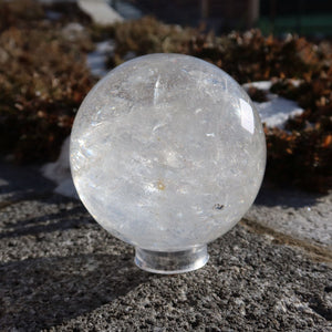 Bergkristall Kugel – Natürliche Kristallkugel 80mm Durchmesser Nr. 30 auf Steinoberfläche, zeigt die klare und natürliche Schönheit des Kristalls.