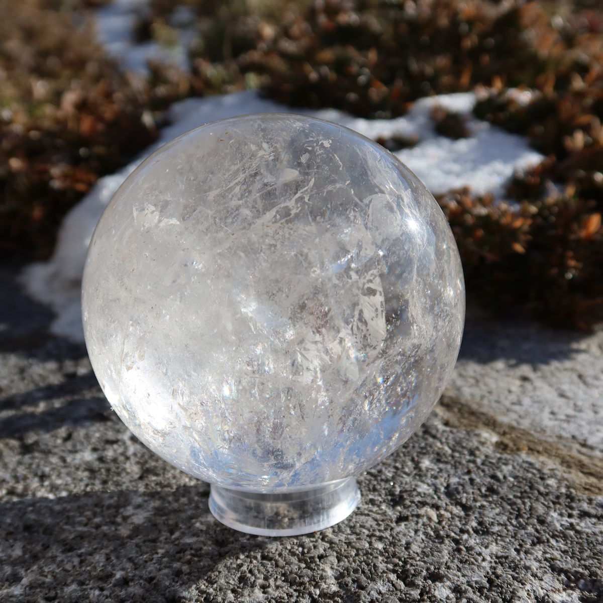 Bergkristall Kugel – Natürliche Kristallkugel 75mm Durchmesser Nr. 31 auf einem Stein im Freien bei Sonnenlicht