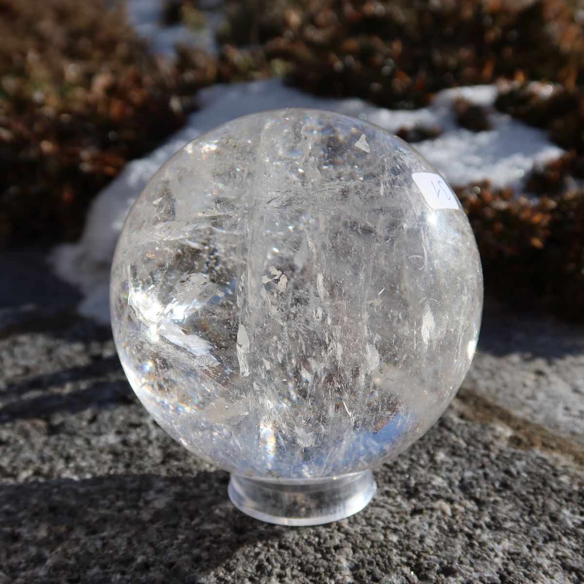 Bergkristall Kugel – Natürliche Kristallkugel 75mm Durchmesser Nr. 31 auf einem Stein im Freien bei Sonnenlicht