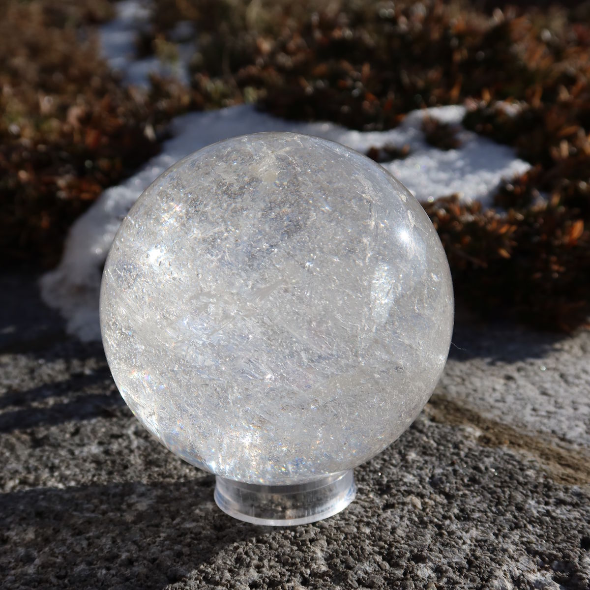 Bergkristall Kugel – Natürliche Kristallkugel 75mm Durchmesser Nr. 32 auf einem Stein im Freien