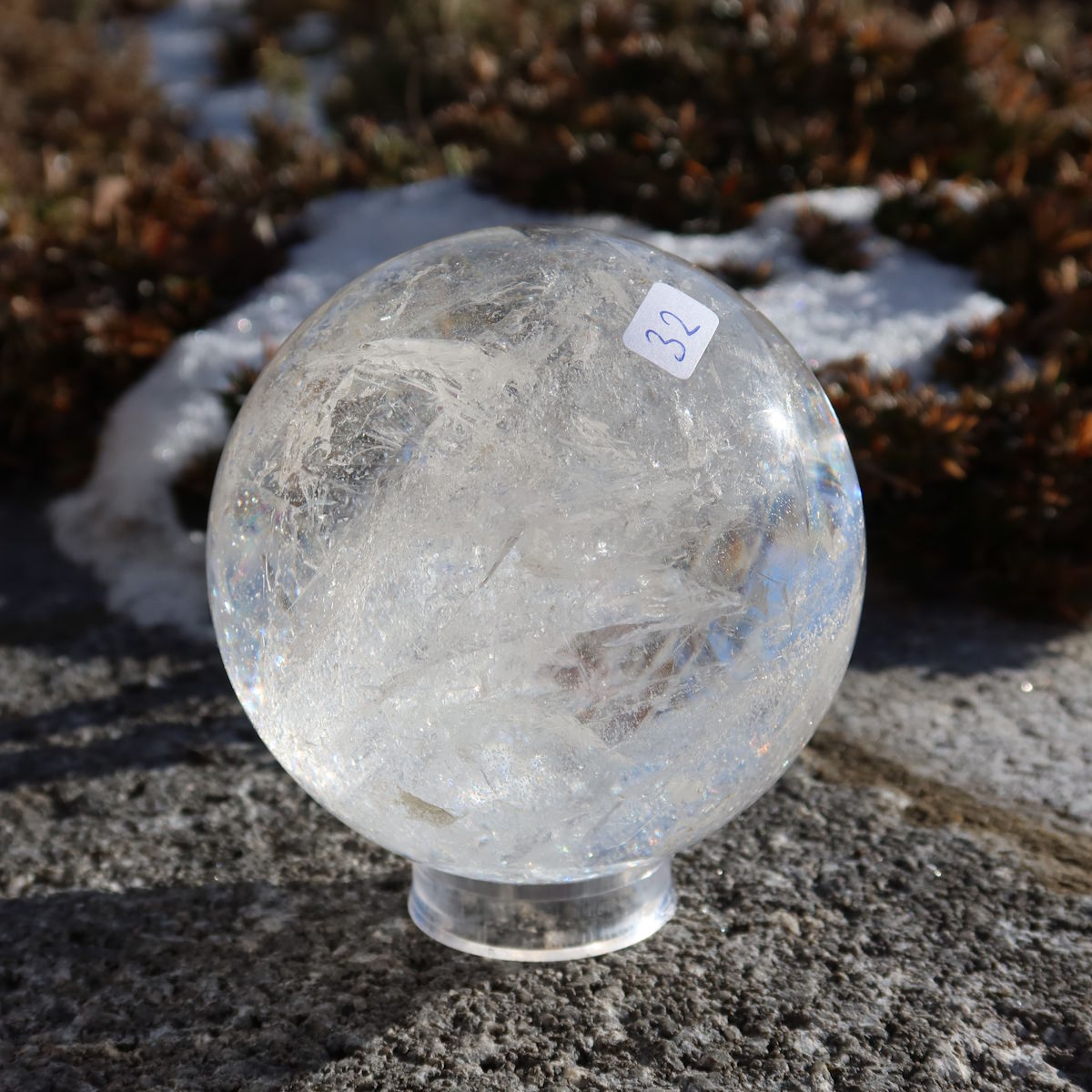 Bergkristall Kugel – Natürliche Kristallkugel 75mm Durchmesser Nr. 32 auf einem Stein im Freien