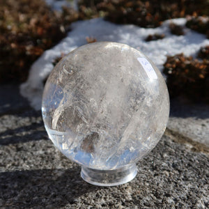 Bergkristall Kugel – Natürliche Kristallkugel 70mm Durchmesser Nr. 33 auf Steinuntergrund im Freien