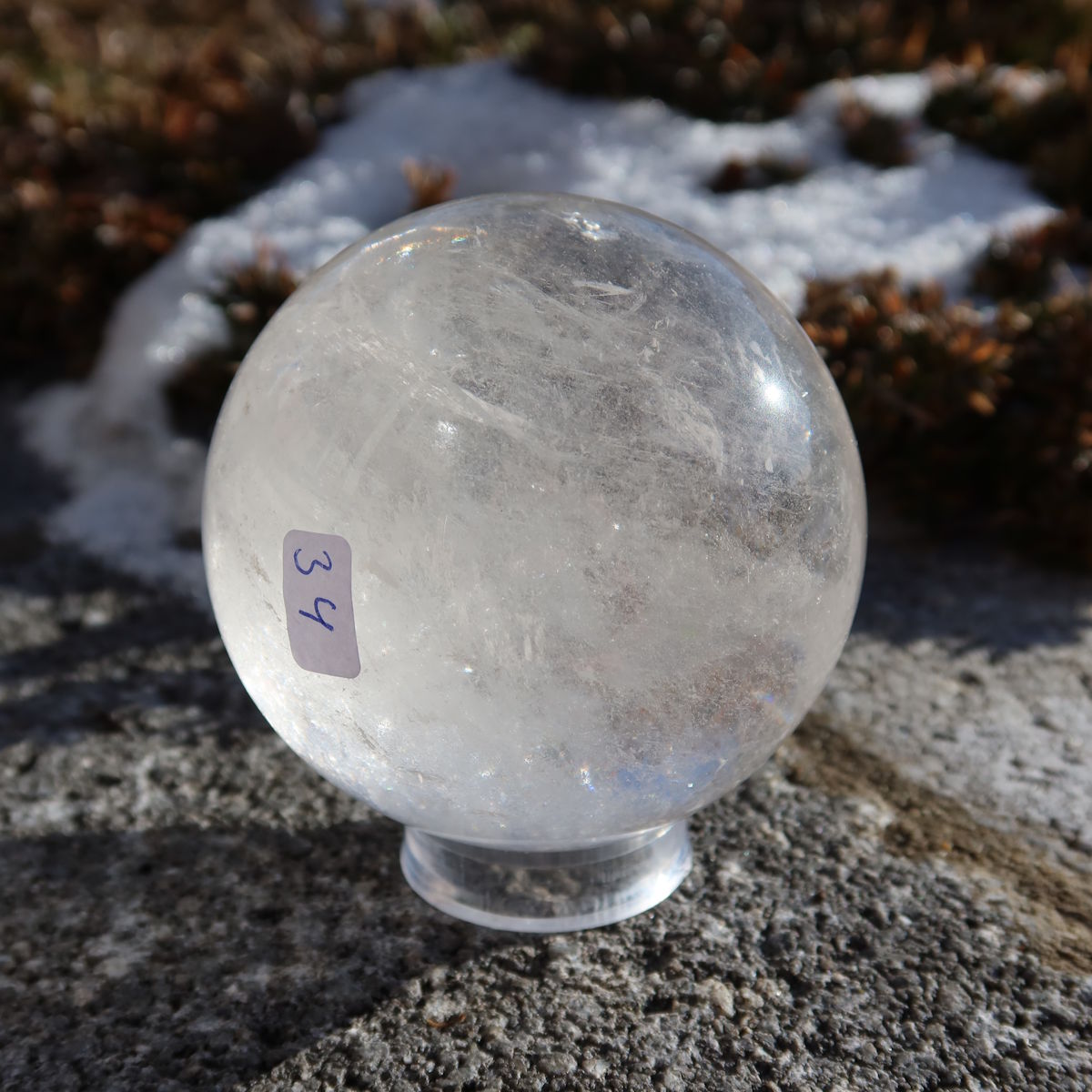 Bergkristall Kugel – Natürliche Kristallkugel 70mm Durchmesser Nr. 34 in der Hand gehalten mit natürlichem Licht im Freien.