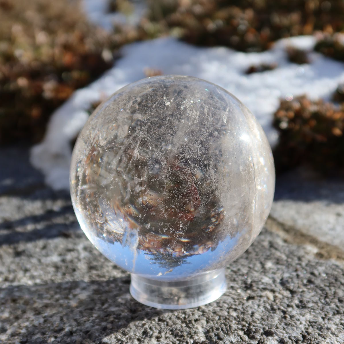 Bergkristall Kugel – Natürliche Kristallkugel 65mm Durchmesser Nr. 35 auf Stein im Freien bei Tageslicht